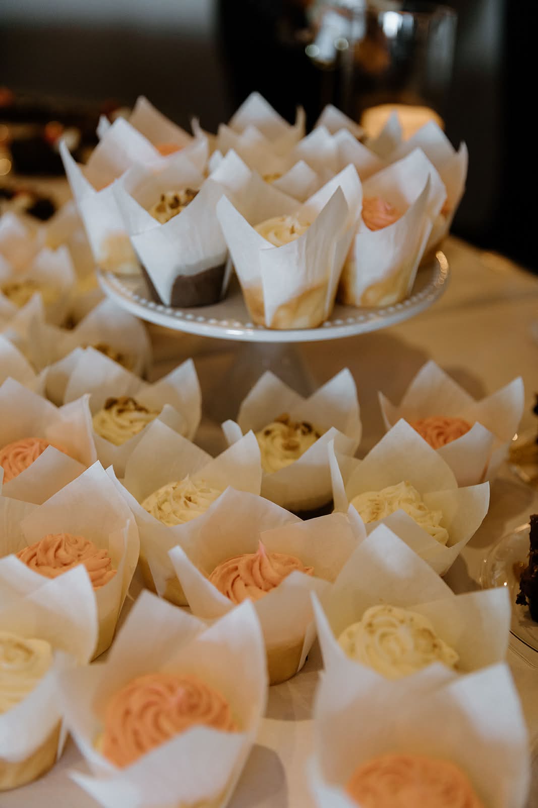 Assorted vanilla and pink frosted cupcakes in tulip wrappers